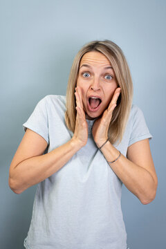 pretty young blond attractive woman posing against blue background and scared and wearing blue tshirt