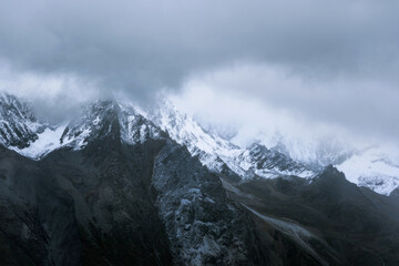 Snow-capped mountain in cloudy sky