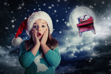 Wall Mural - Cute little child and Santa Claus flying in his sleigh on background. Christmas celebration