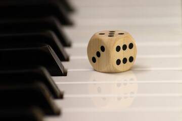 one dice lies on the piano keyboard, background showing the game