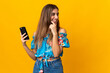 © luismolinero - Young woman using mobile phone over isolated yellow background thinking an idea and looking side