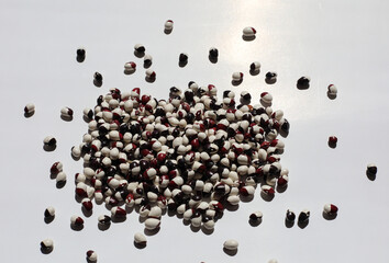 Macro view of black and white haricot bean. Pile of two colors legumes close up on a white paper background.