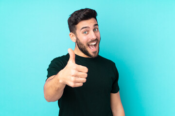 Caucasian handsome man isolated on blue background with thumbs up because something good has happened