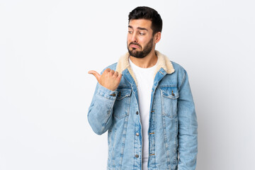 Poster - Young handsome man with beard isolated on white background unhappy and pointing to the side