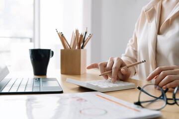 Close up Business woman or accountant using calculator with computer laptop, Business accounting, budget and loan paper at home