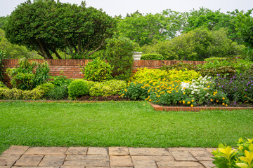 backyard english cottage garden on brown pavement and green lawn