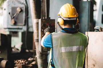 Back view of Work at factory.Asian worker man  working in safety work wear with yellow helmet .in factory workshop industry machine professional