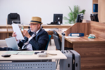 Old male employee preparing for travel in the office