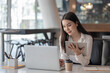 © amnaj - Beautiful Asian woman working on a laptop holding a tablet at the office.