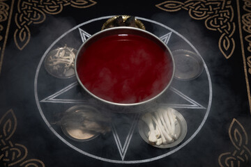 Goblet with blood on ritual table. Dark room with smoke. Black magic, occult concept. Witchcraft and rituals. 