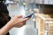 © DG PhotoStock - Woman using a smartphone when shopping in the store.