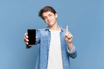 young boy smiling and looking friendly, showing number one or first with hand forward, counting down