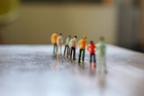 Fototapeta Most - Miniature figurine character queuing on the one line by social distancing, selected focus, Covid 19 concept