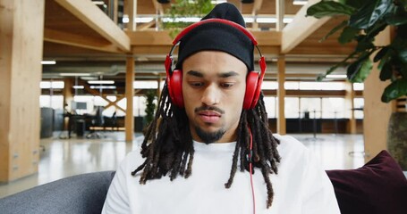 Wall Mural - Young designer listening to music on
headphones at work
