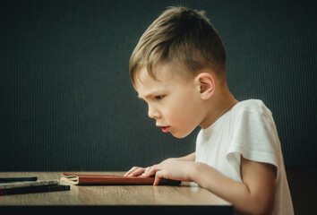 little boy writes on a gray background