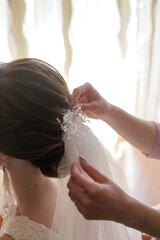 Wall Mural - bridesmaid puts on the bride's hair a veil