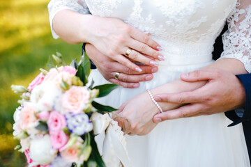 Wall Mural - the bride holds a bouquet in her lowered hand, the groom hugs her waist from behind