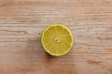 Wall Mural - Top view of freshly harvested fruits. Sweet juicy half cut lime on wooden table. Healthy eating vitamin C.Summer tropical fruit food concept flat lay.Ripe organic citrus.Lime sour slice isolated.