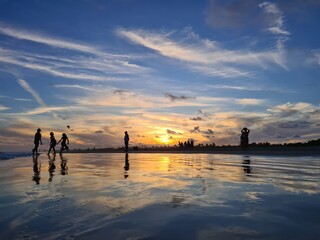 Wall Mural - Silhuetas de pessoas em um por do sol na praia