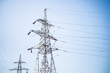 Metal supports of electric transmission lines on a blue sky background.