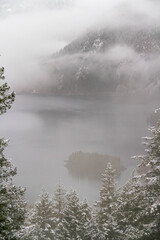 Wall Mural - A mountain lake in winter surrounded by snow covered pine trees.