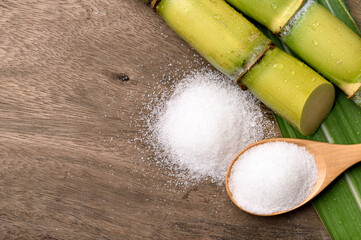 Wall Mural - Flat lay (top view) of White sugar with fresh sugar cane on wood background.