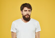 © SHOTPRIME STUDIO - Portrait of a sad man on a yellow background cropped view of a white t-shirt