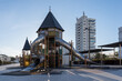 Parque infantil con juegos y tobogán, ciudad de fondo