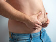 The man in jeans squeezes his hairy, flabby, fat stomach. The concept of poor nutrition. body positive. Self-acceptance