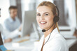 © Iryna - Blonde business woman using headset for communication and consulting people at customer service office. Call center. Group of operators at work