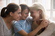 © fizkes - Overjoyed three generations of Caucasian women relax together cuddle in cozy home at family weekend. Happy little girl child with young mother and older grandmother rest showing unity and bonding.