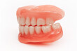 Full removable plastic denture of the jaws. Set of dentures on a white background. Two acrylic dentures. Upper and lower jaws with fake teeth. Dentures or false teeth, close-up.