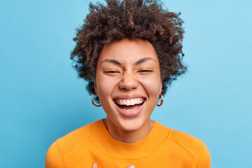 close up shot of beautiful young african american woman with natural curly hair smiles broadly has p