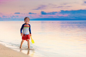 Child playing on ocean beach. Kid at sunset sea.