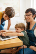 Boy using laptop with brother and mother at home