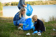 volunteering, charity, people and ecology concept, volunteers using garbage bag while collecting litter