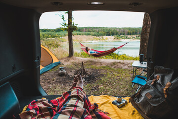 Wall Mural - person view couple resting at camping woman laying in hammock with beautiful view of forest lake