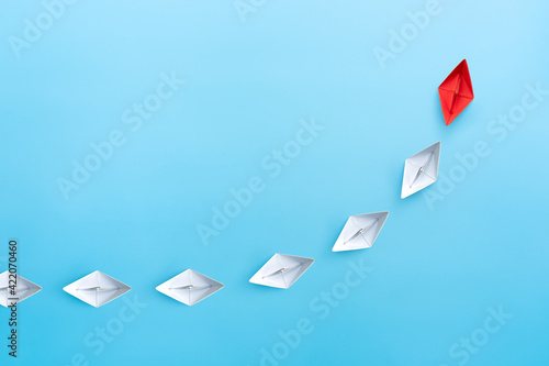 Obraz Dibond Leadership concept with red leader paper ship leading among white on blue background. copy space