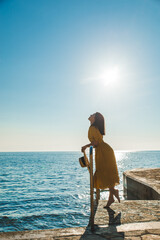 Wall Mural - young pretty woman in yellow sundress at sea beach