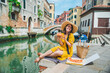 © phpetrunina14 - woman sitting on pond with view of venice canal eating pizza