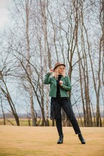 Woman Wear Eco Leather Green Jacket, Fedora Brown Hat And Vintage Aviator Glasses , Belt With A Fringe, Trendy Concept