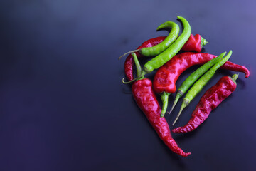 Canvas Print - Top view of a group of red and green chili peppers on the dark background with a copy space