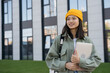© ARUTA Images - Portrait of smiling asian woman holding laptop computer looking away on the street. Happy student walking to university