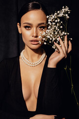 beautiful woman with dark hair in elegant clothes posing with flowers