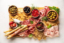 Appetizers With Differents Antipasti, Charcuterie, Snacks And Red Wine On White Background. Sausage, Ham, Tapas, Olives And Crackers For Buffet Party. Top View, Flat Lay