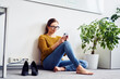 © baranq - Businesswoman sitting using mobile phone sitting on floor in office