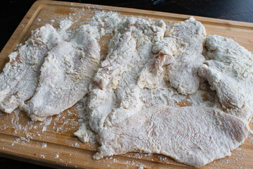 Wall Mural - Raw Breaded Chicken Cutlets: Raw thinly sliced chicken breasts covered in flour on a bamboo cutting board