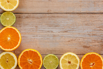 Wall Mural - Oranges,limes and lemons slides on wooden table view from above.Beautiful background with fresh fruit half cut.Healthy eating vitamin C.Summer tropical fruits food concept flat lay.Creative frame.