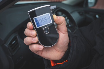 a man with a breathalyzer in the car