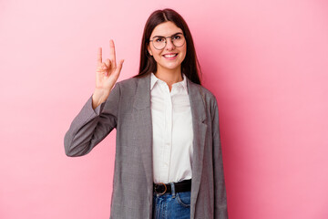 Wall Mural - Young caucasian business woman isolated on pink background showing a horns gesture as a revolution concept.